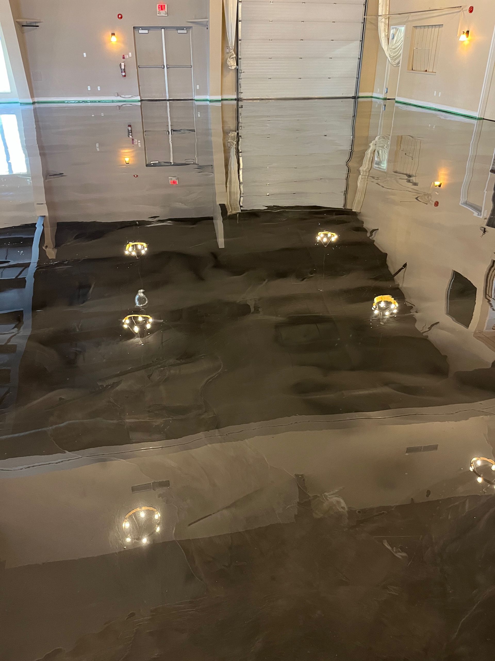A shiny black floor in a room with a garage door in the background.