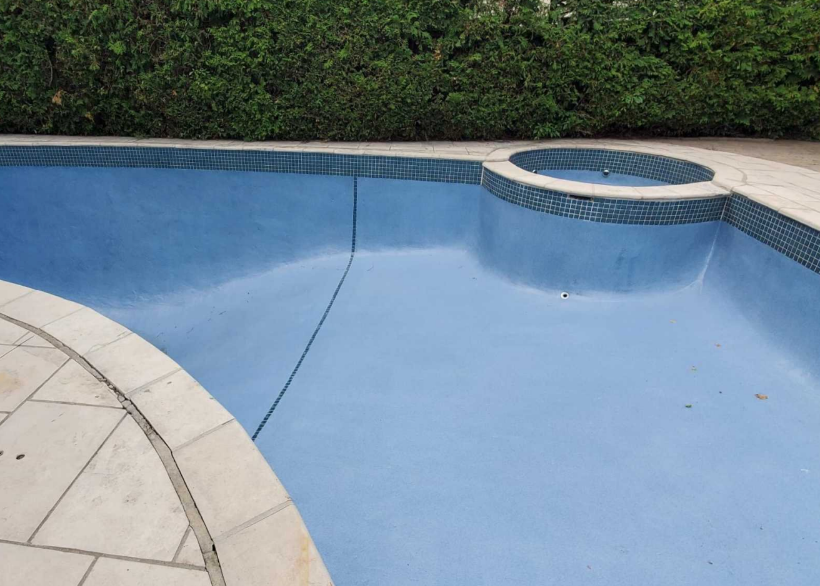 A large blue swimming pool with a spa in the middle