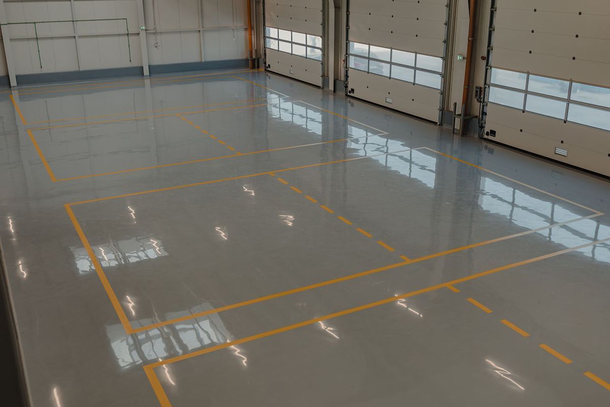 A large empty warehouse with a lot of doors and lines on the floor.