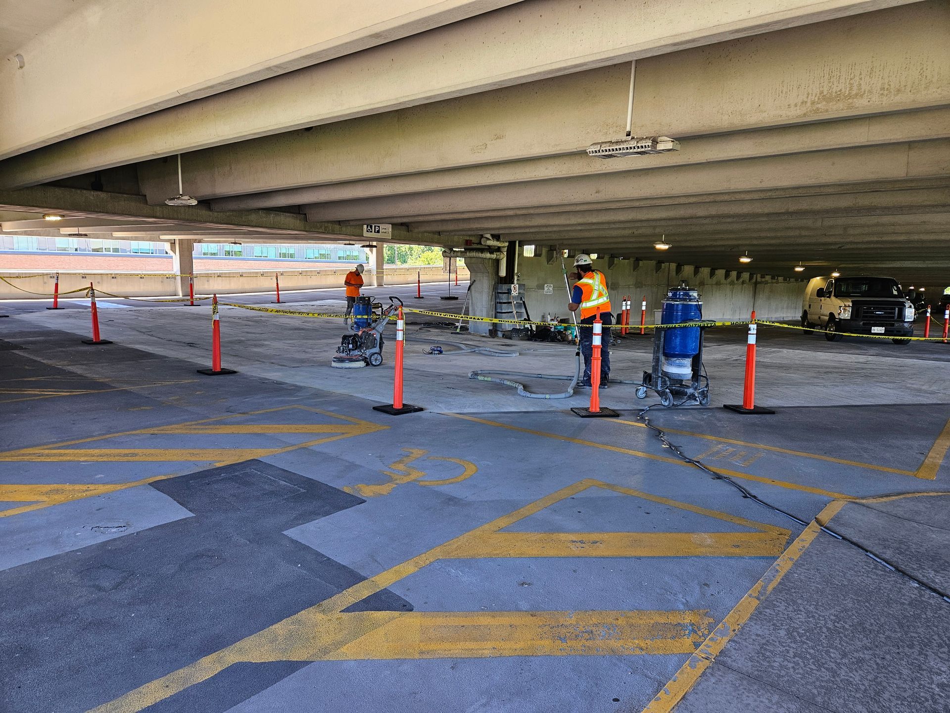 A man is working on a parking lot under a bridge.