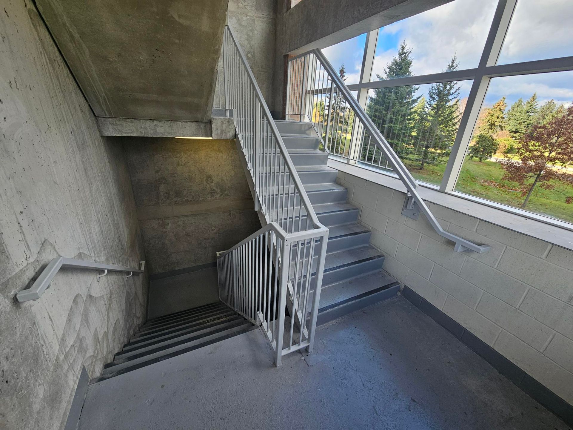 A staircase in a building with a railing and a window.