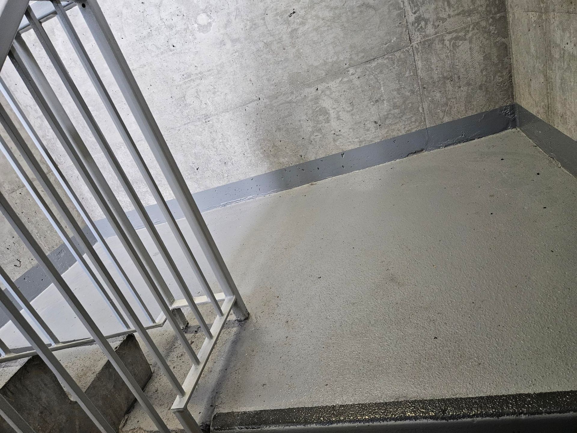 A staircase with a metal railing and a concrete wall.