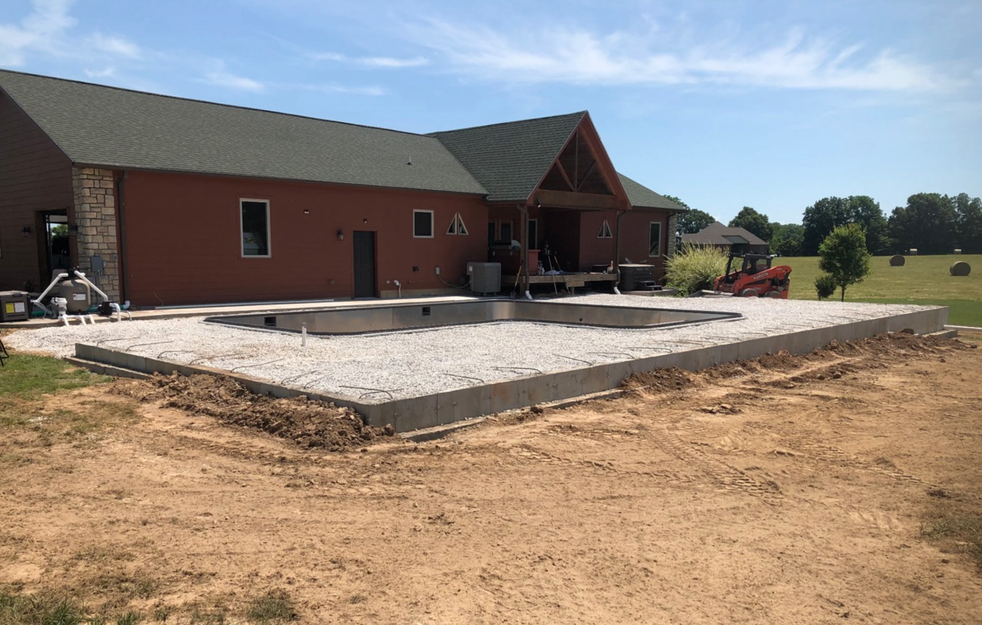 Brick house with a large new concrete patio under construction in a rural yard
