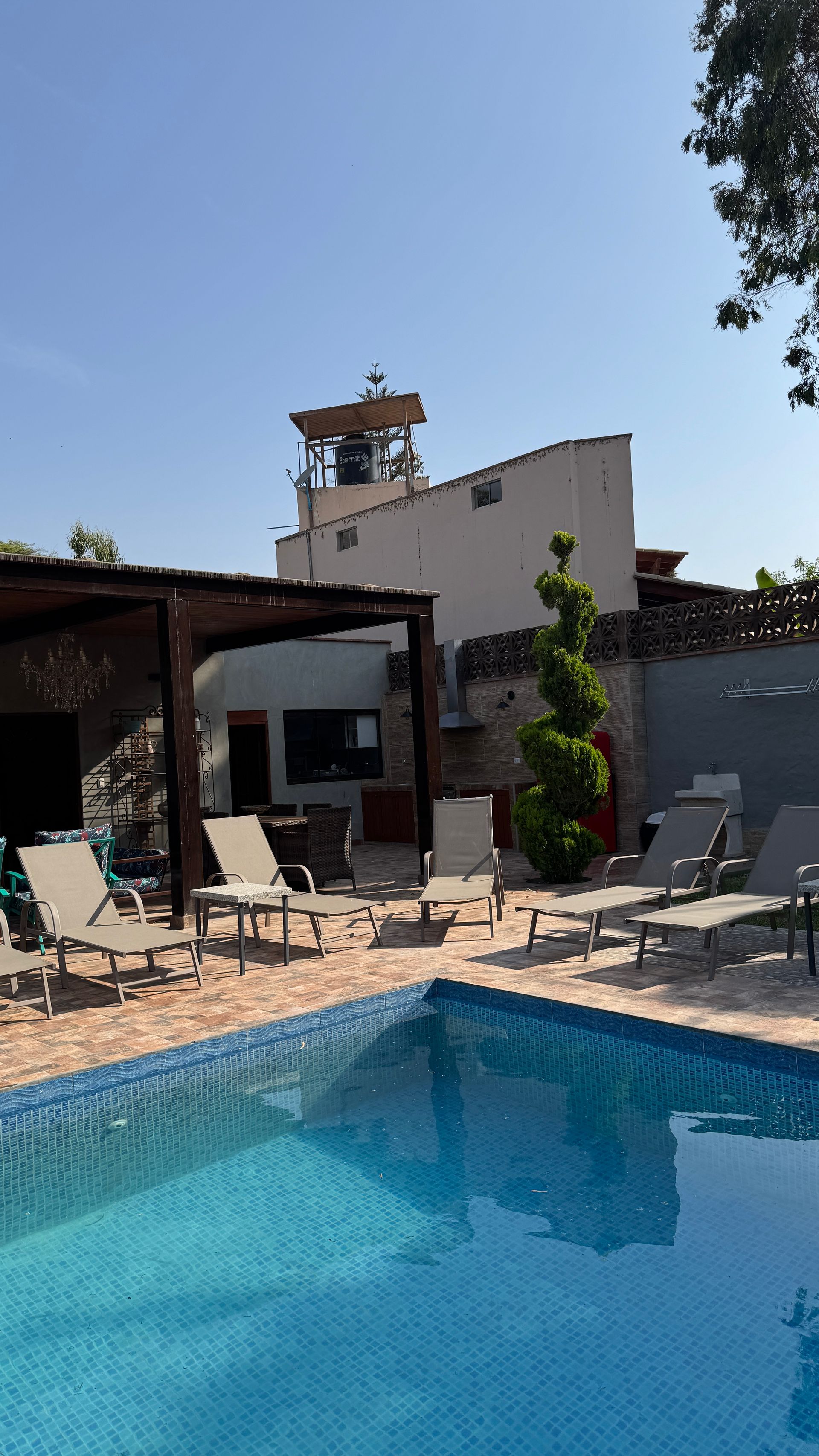 Poolside scene with lounge chairs, blue water, and white building under a clear sky.