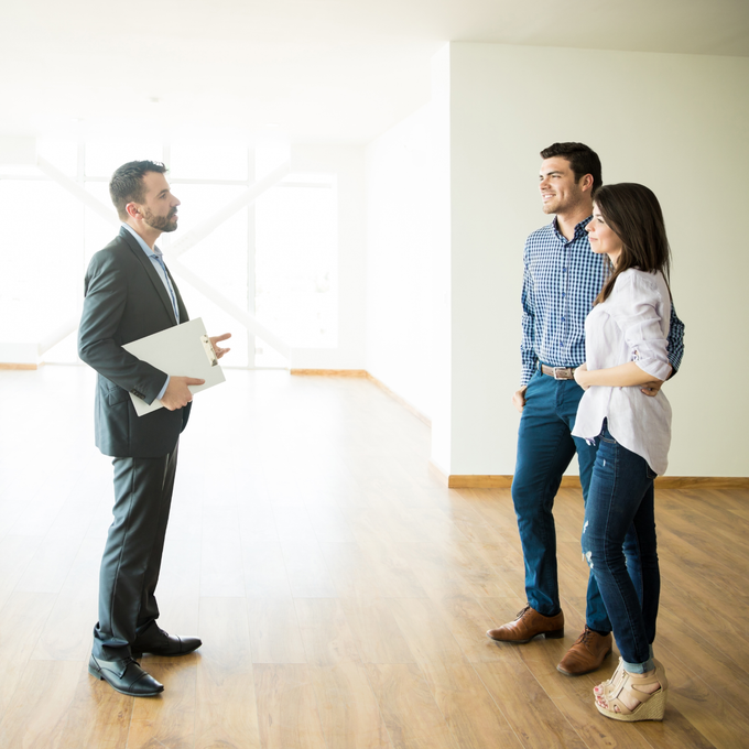 Businessman speaking with a couple in a bright office lobby