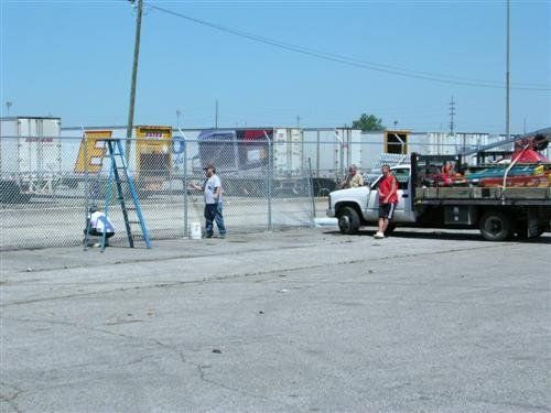 Workers painting a chain-link fence