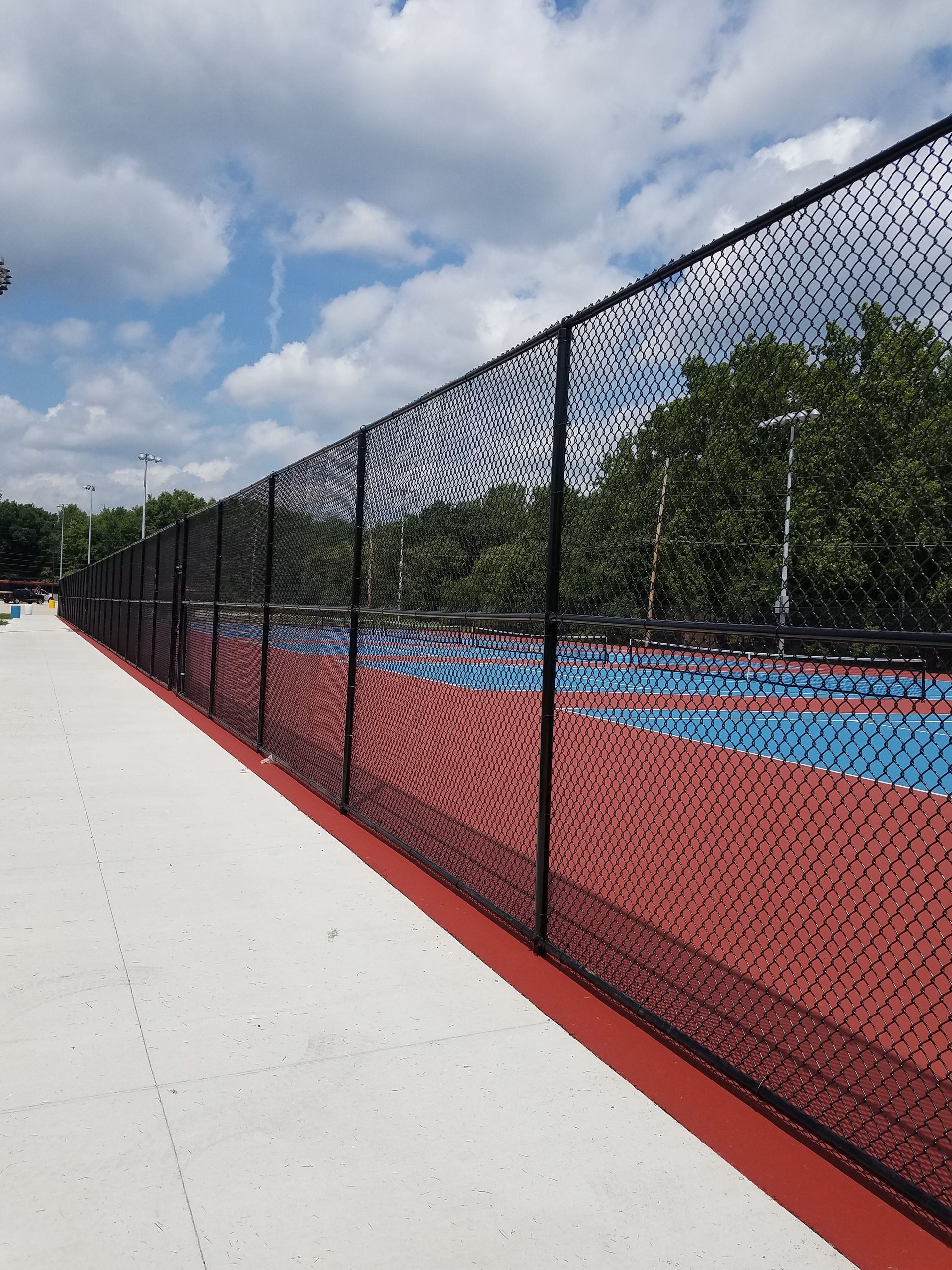 Black chain-link fence along a red and blue sports court