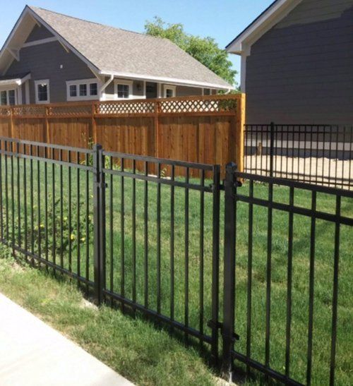Black metal fence in front of a wooden fence
