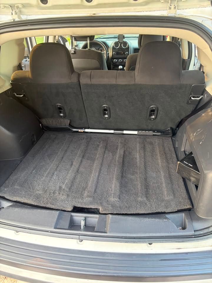 Open car trunk with folded rear seats and a black cargo mat.