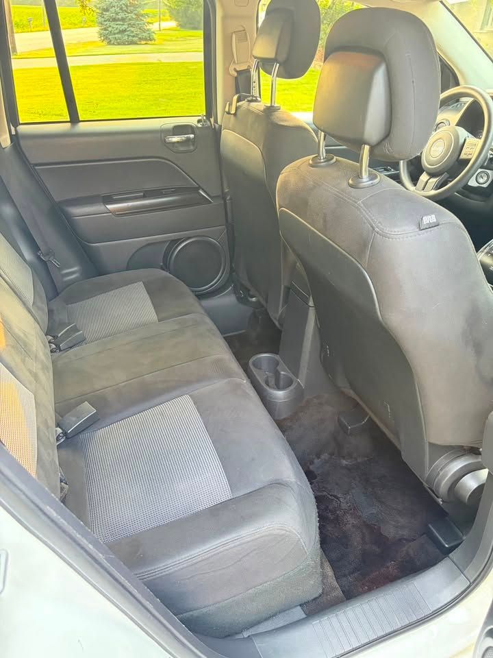 Back seat of a vehicle with gray upholstery and cup holders, viewed from the rear door.