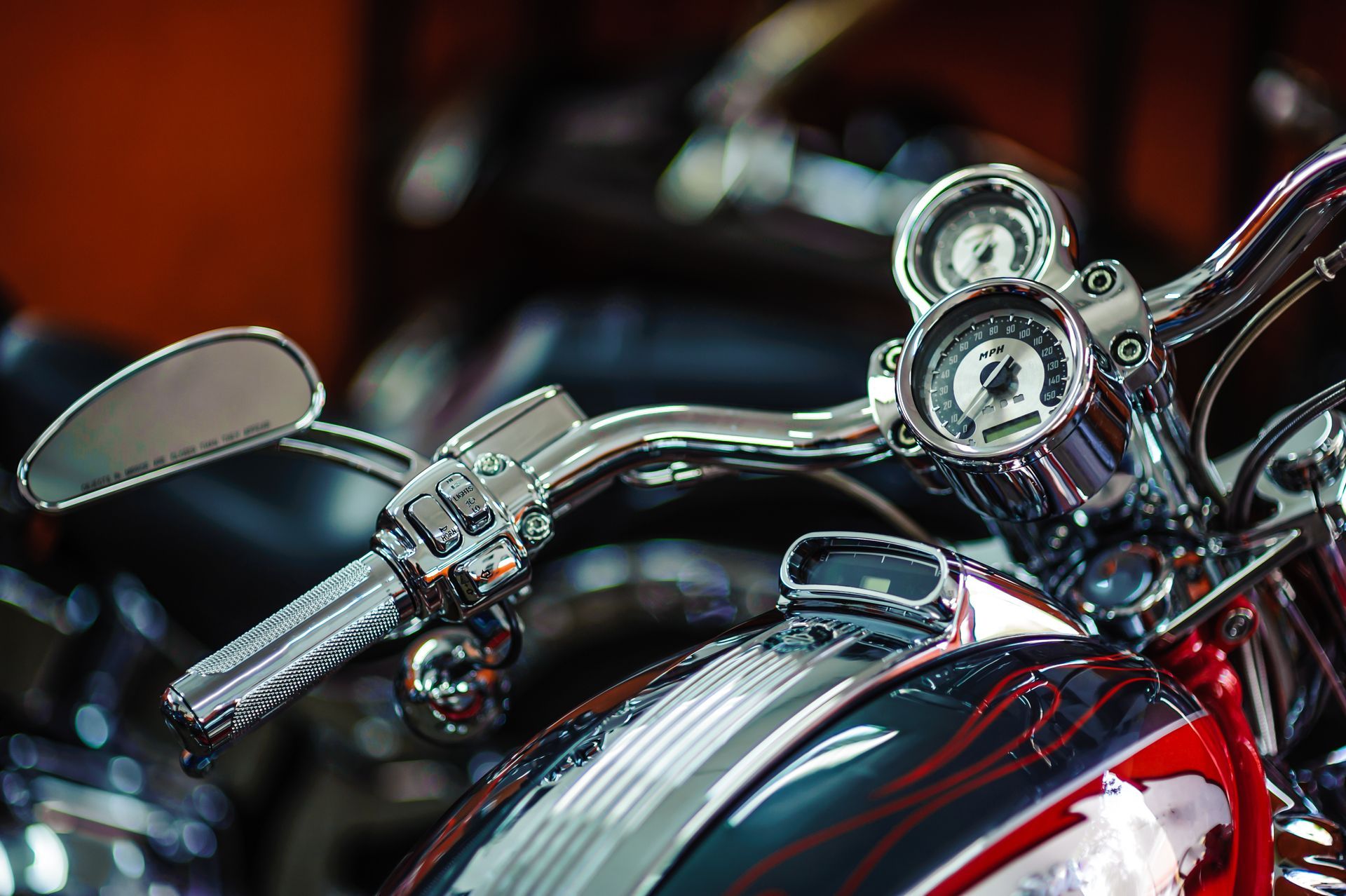 Close-up of a red motorcycle’s chrome handlebars and gauges with a blurred background