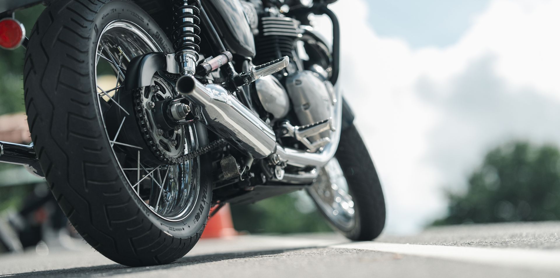 Close-up of a motorcycle leaning on a road with a blurred outdoor background
