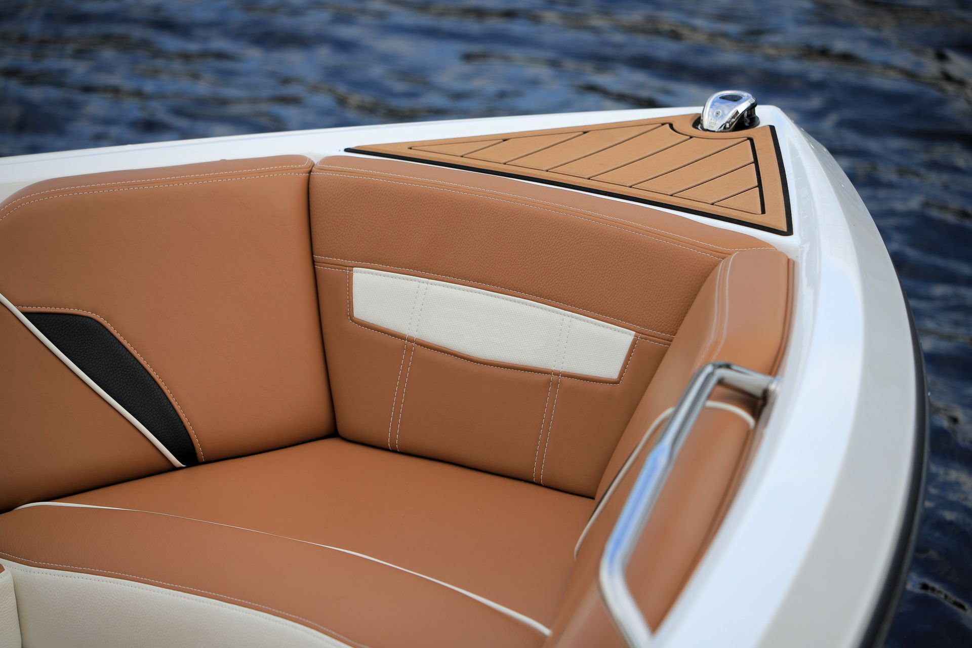 Tan leather boat seat with white accents beside dark blue water