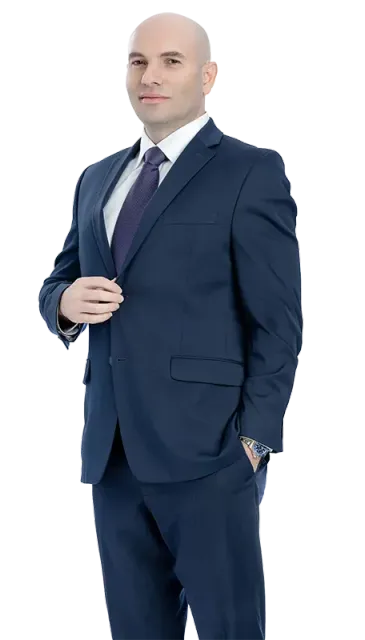 A man in a suit and tie is standing with his hands in his pockets.