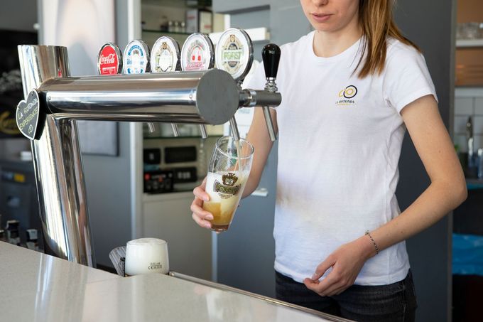 Un barista versa la birra da un rubinetto in un bicchiere al bancone.