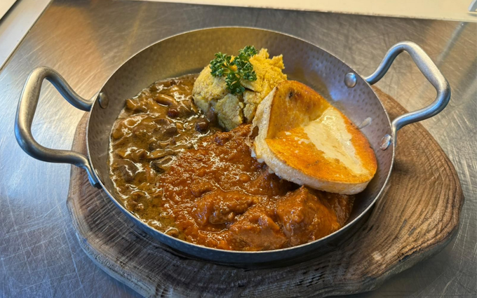 Bistecca scottata in padella su polenta gialla cremosa in una padella grigia poco profonda su un tagliere di legno.