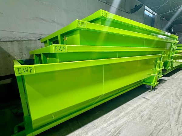 Stacked bright green industrial metal bins in a warehouse or factory setting.