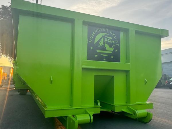 Bright green industrial dumpster with front opening and logo, shown outdoors on a lot.
