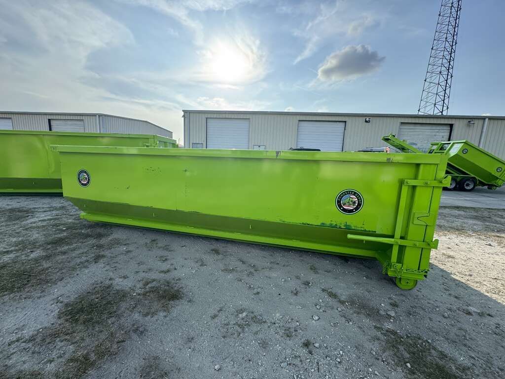 Bright green industrial metal trailer or conveyor on a gravel lot under a cloudy sky