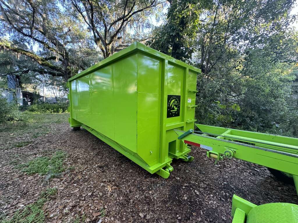 Bright lime-green shipping container on a trailer in a wooded outdoor area