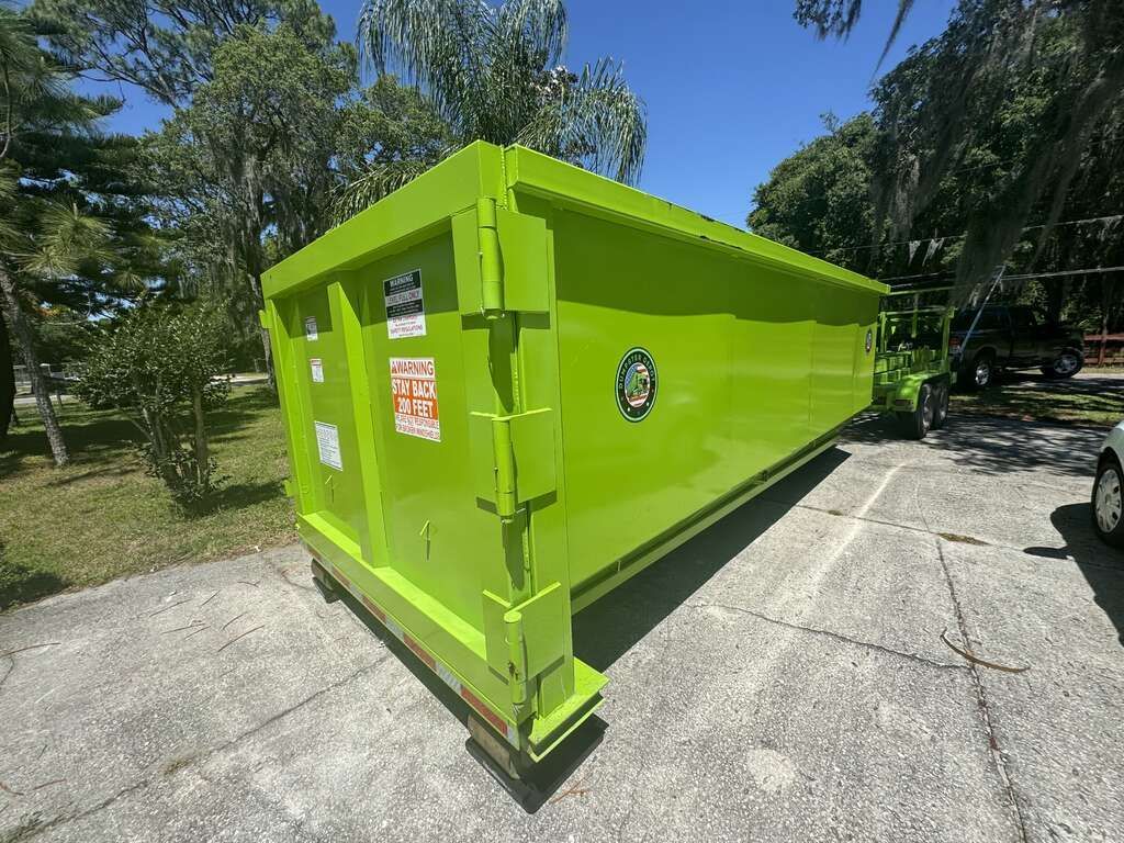 Bright green industrial dumpster on a concrete pad in a sunny outdoor area