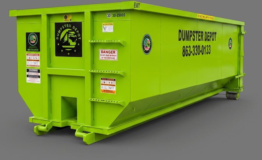 Large black dumpster on a driveway in a suburban neighborhood at dusk.