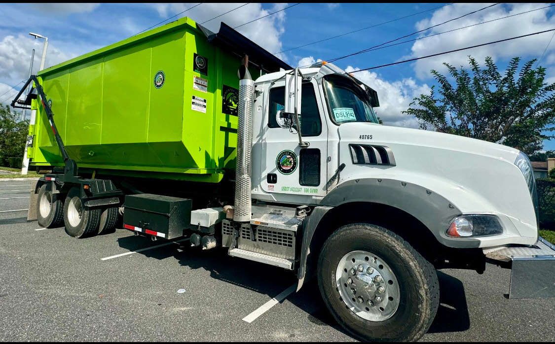 Bright green dump truck parked on a road under a blue sky