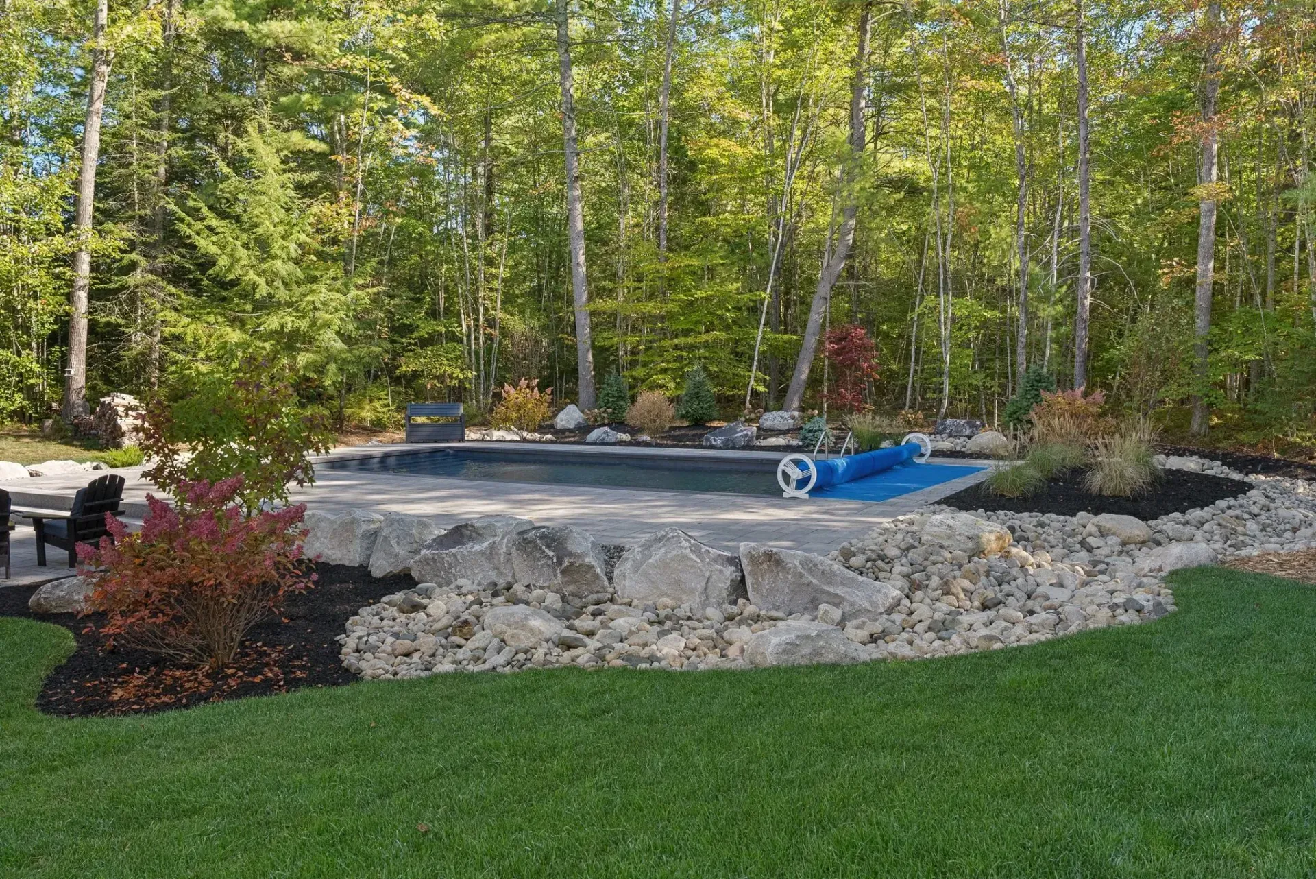 Rock garden with a blue pondless fountain and trees in a landscaped yard
