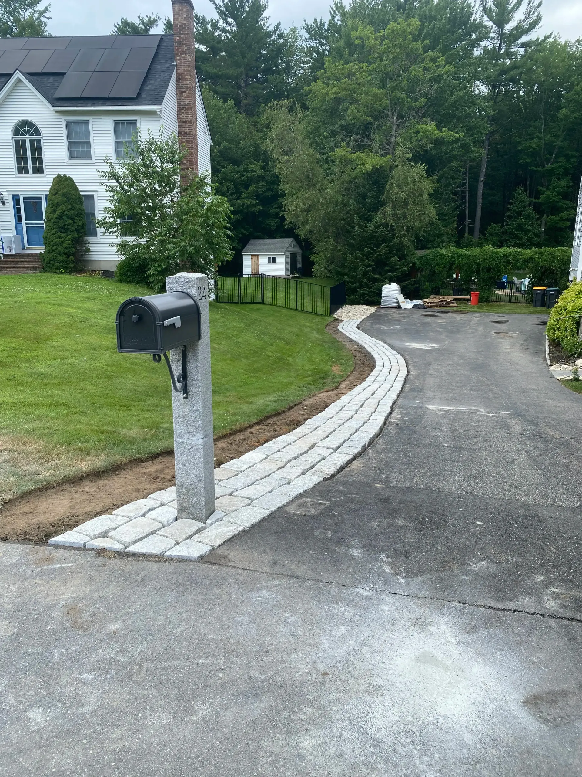 Driveway with newly installed stone pathway leading to a mailbox near a white house.