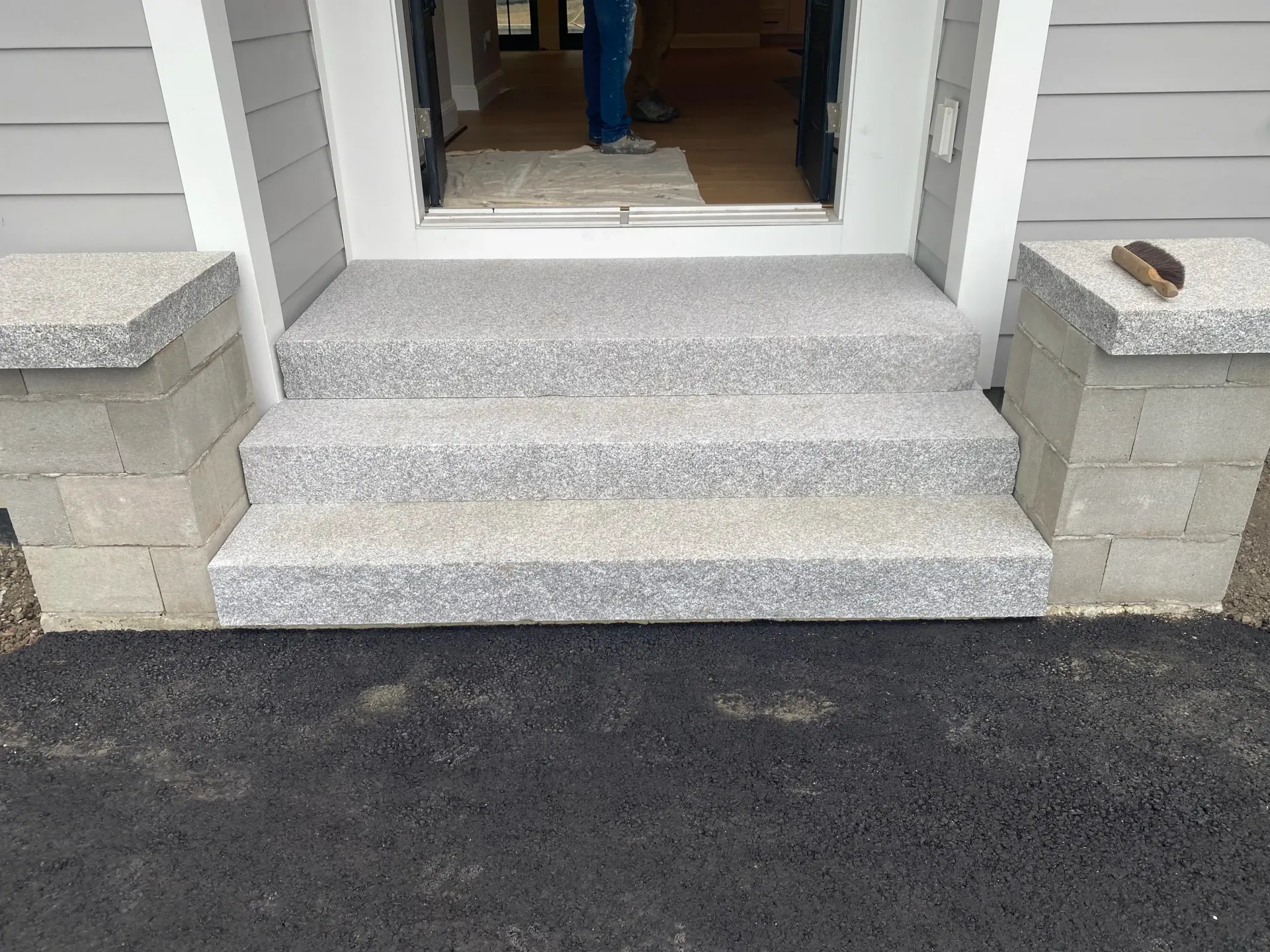 Exterior gray speckled steps leading to a doorway. Concrete pillars on either side.