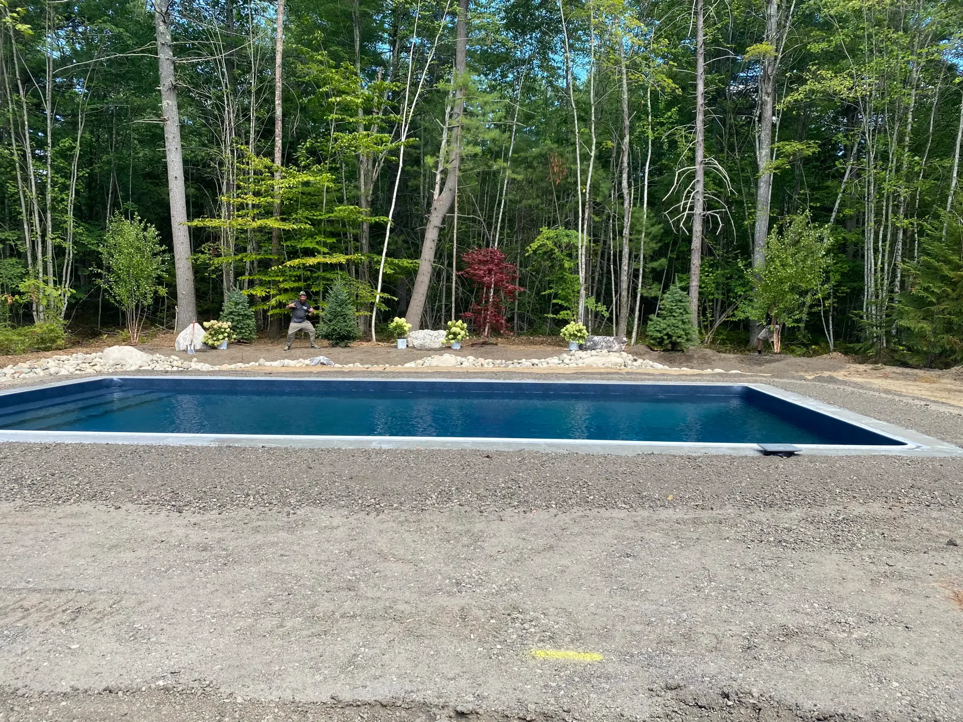 Rectangular pool surrounded by gravel, with trees in the background.