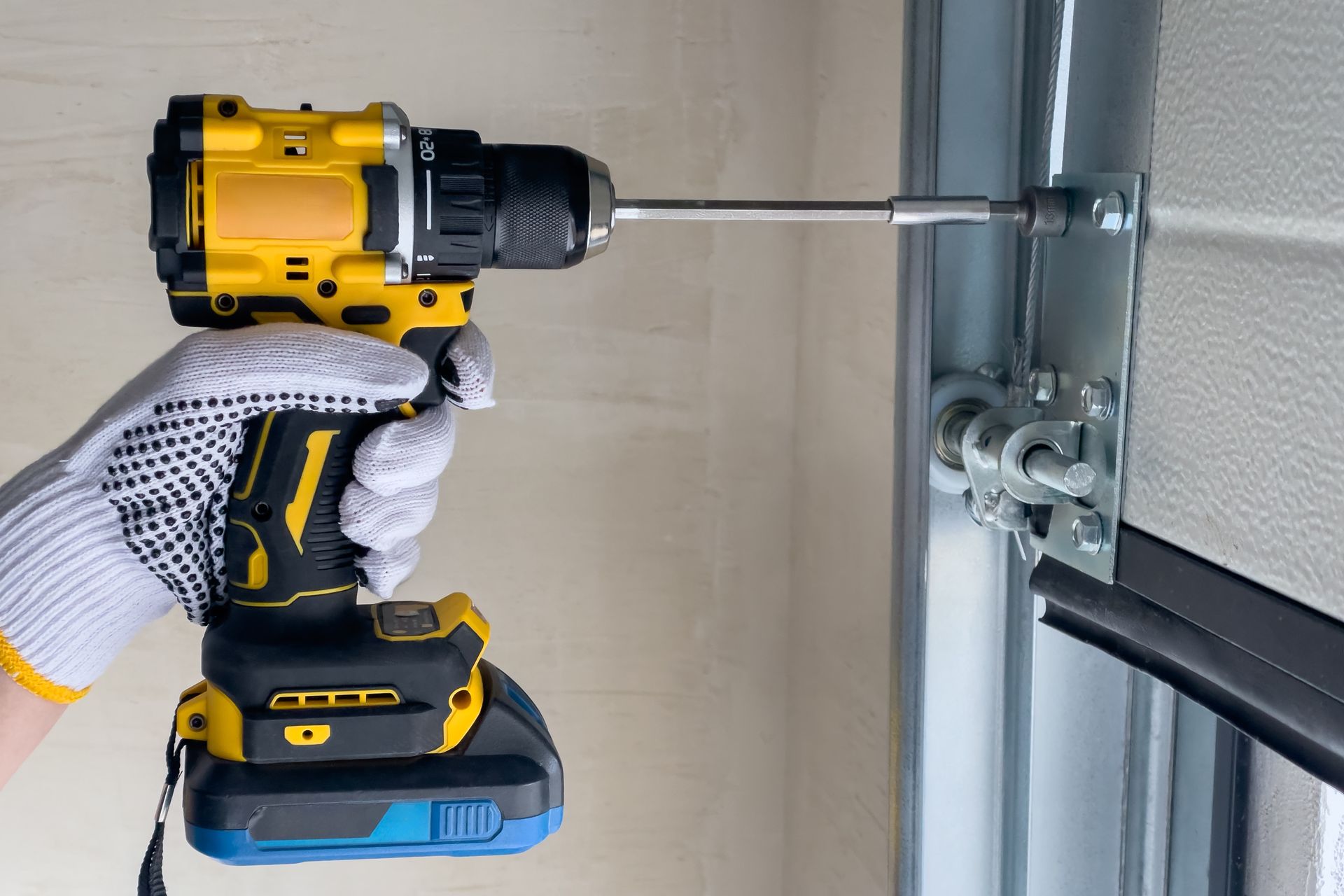 Person using a yellow and black drill to screw into a garage door frame.