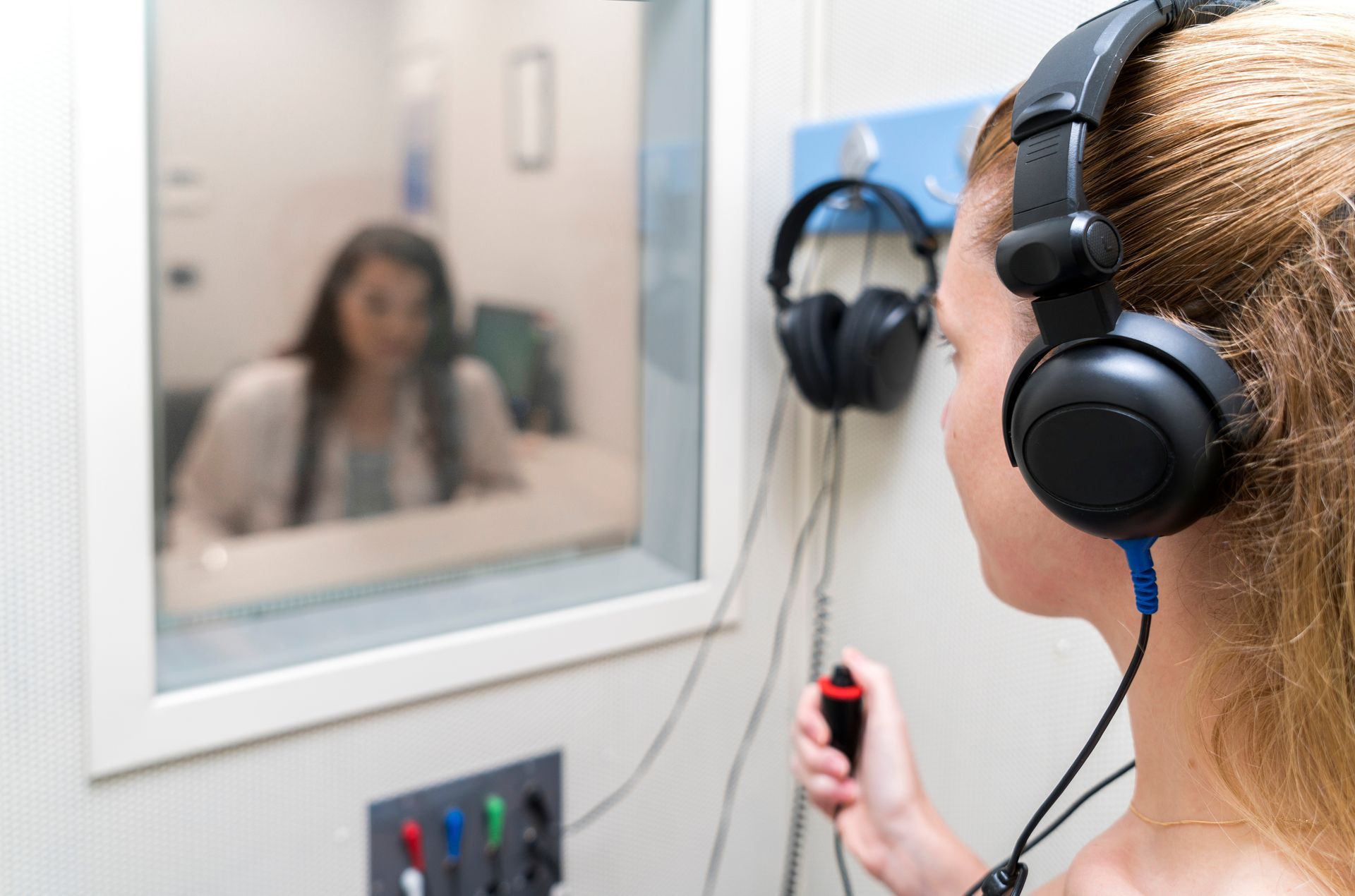 Patient taking a hearing test in a sound booth at an audiologist in Redmond, OR