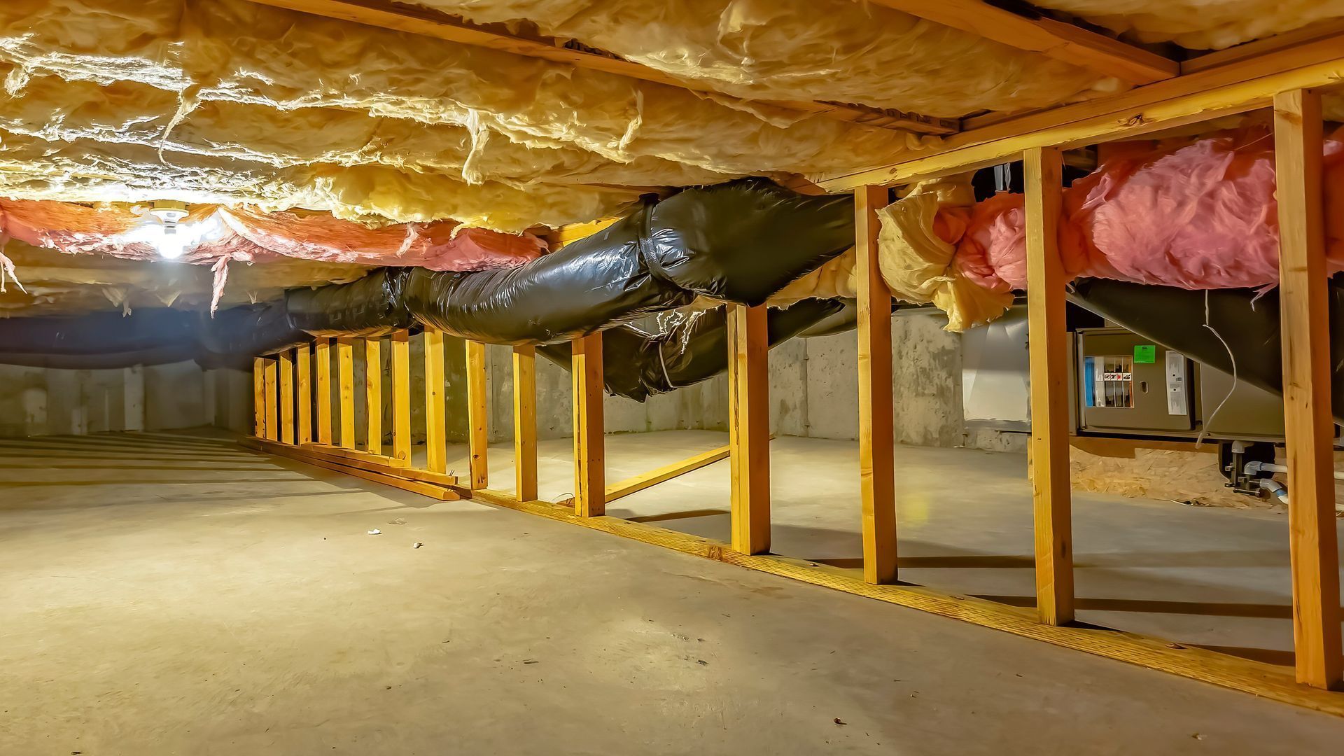 Unfinished basement with exposed insulation, wooden supports, and a concrete floor