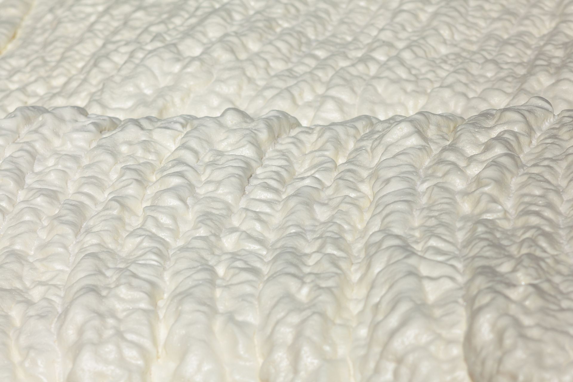 Close-up of a white textured knitted fabric with a raised ribbed pattern