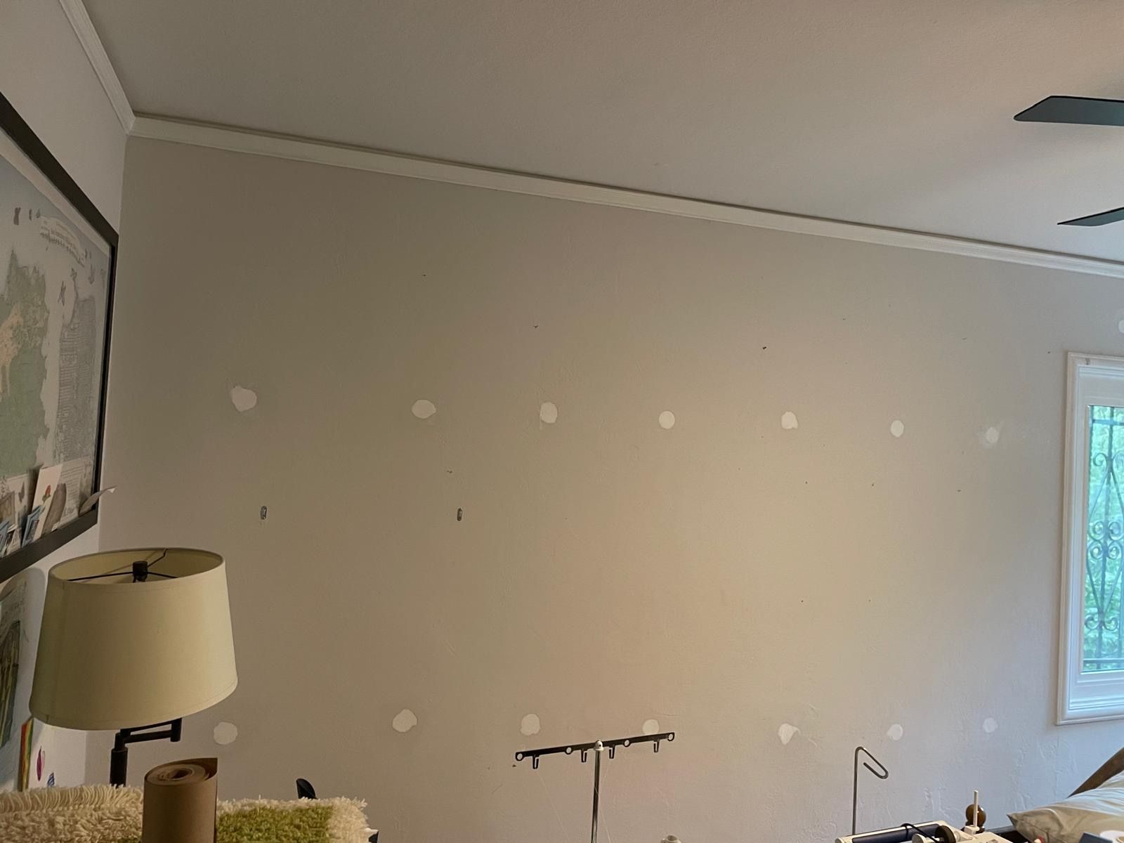 Empty beige wall with several patch spots in a sparsely furnished room