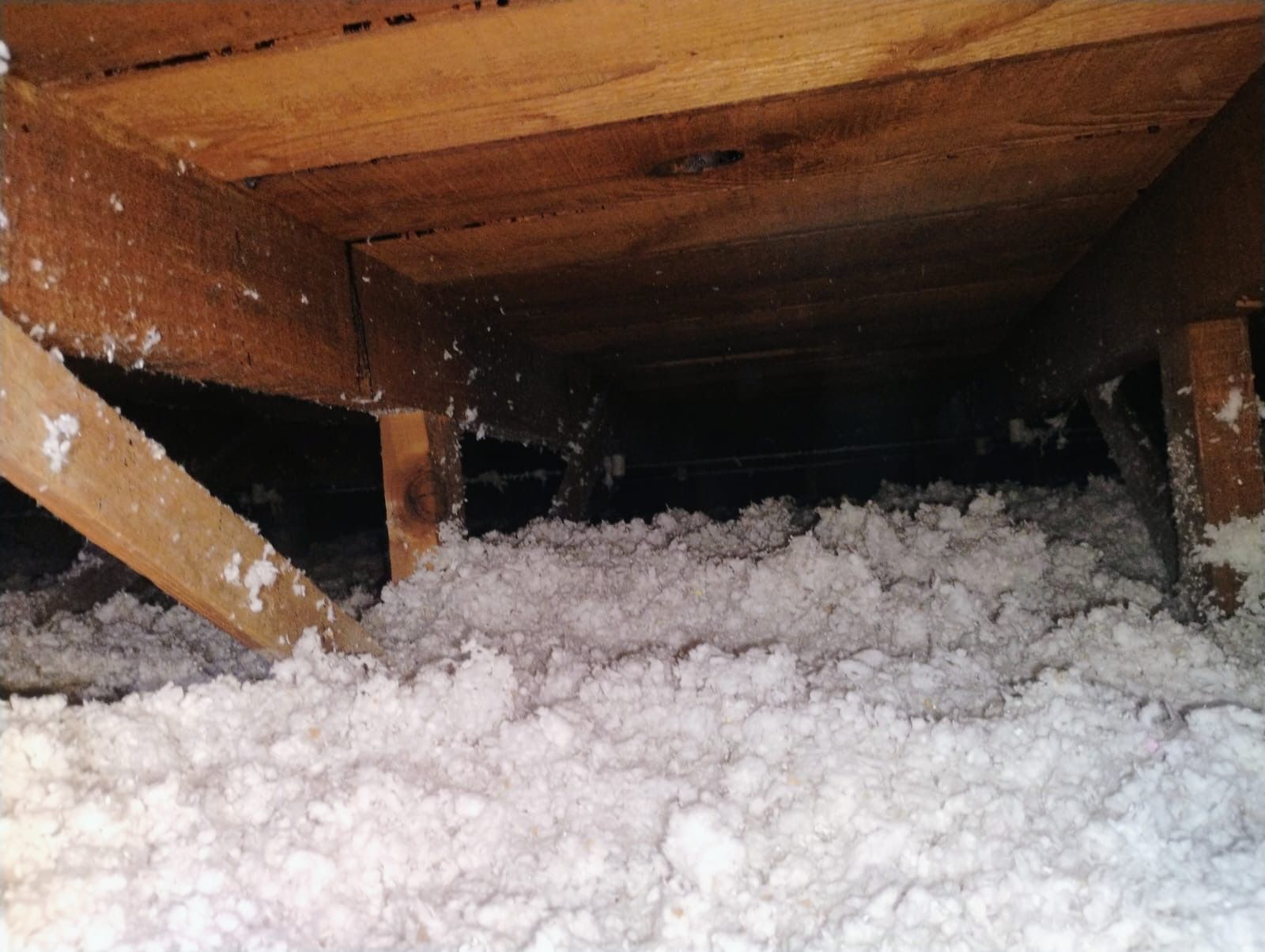 Snow packed under a wooden deck with support beams visible