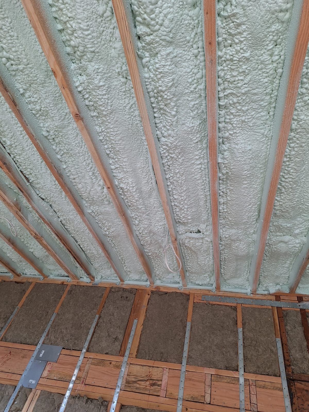 Spray-foam insulated ceiling with exposed wooden rafters and insulation battens
