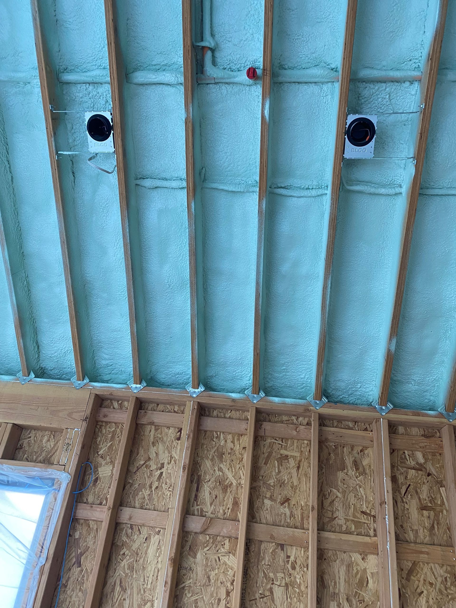 Blue ceiling with exposed beams and two dark circular fixtures above a textured tan wall