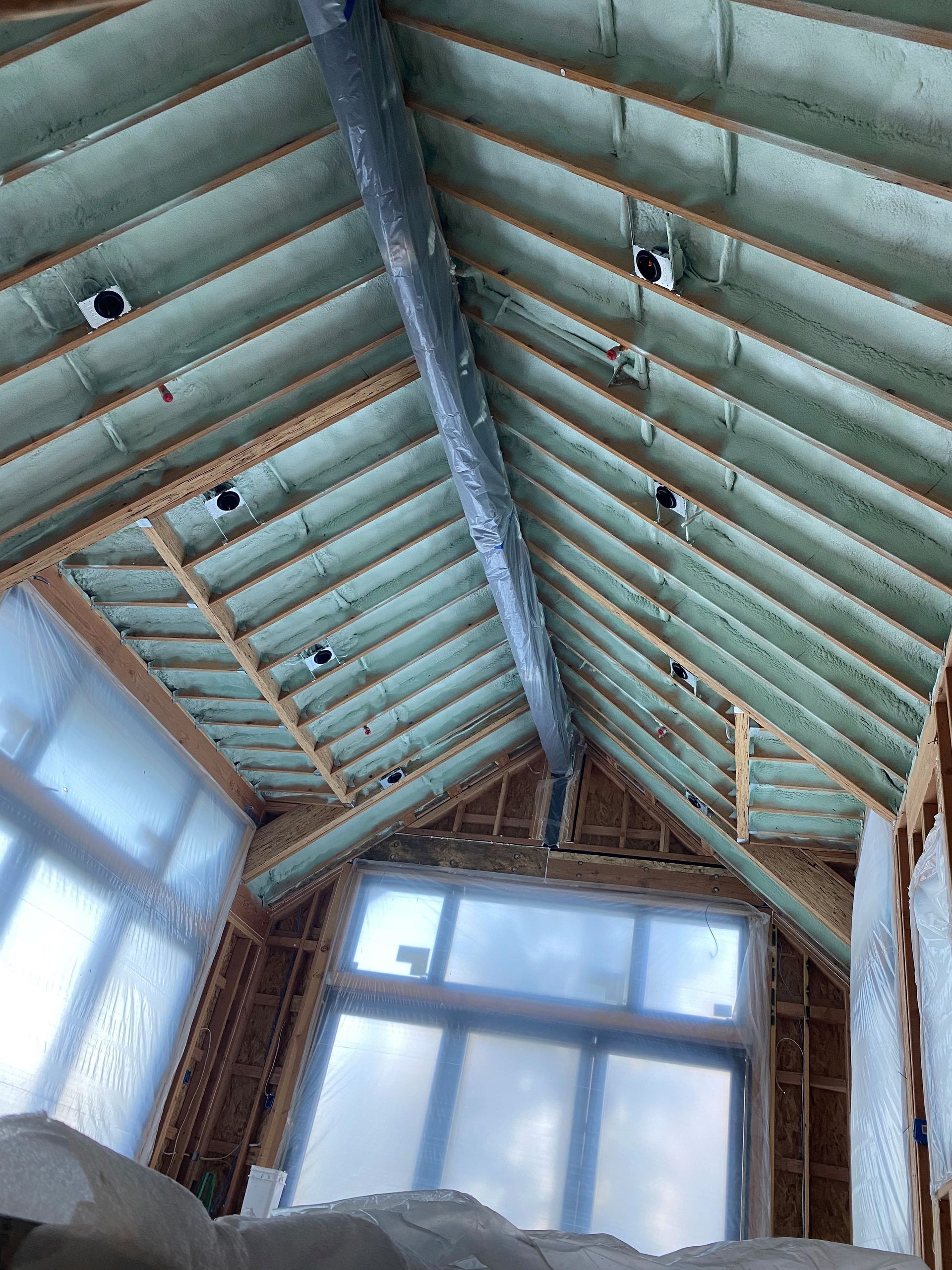 Interior with a peaked wooden ceiling, exposed beams, and large windows letting in daylight.