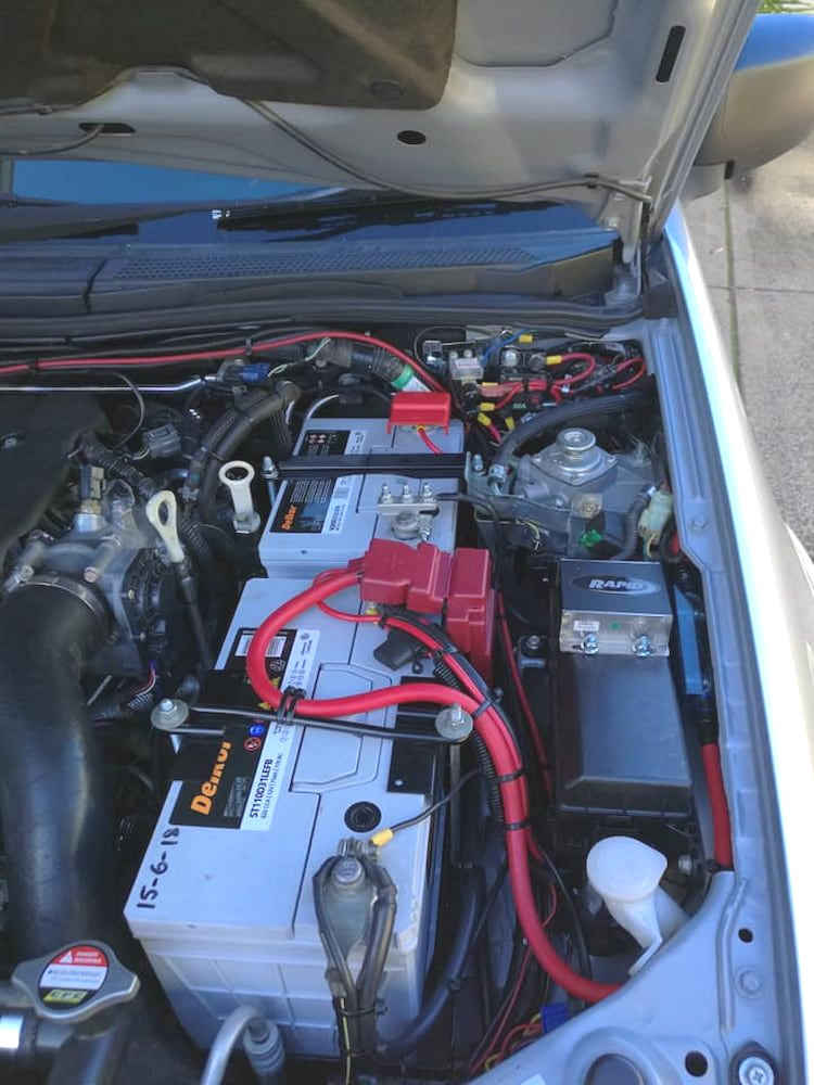 Car Engine Bay With Two Car Batteries, Red Wiring, and a Black Air Intake — D R Automotive in Russell Vale, NSW
