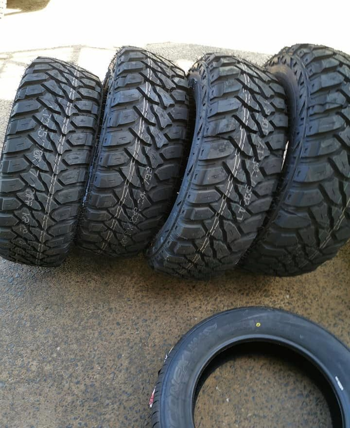 Four Black Off-road Tires and One Smooth Tire on a Grey Concrete Surface — D R Automotive in Russell Vale, NSW