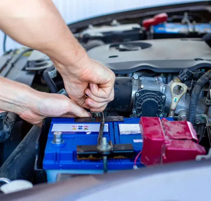 A Mechanic Replacing A Battery In A Car Engine — D R Automotive in Russell Vale, NSW