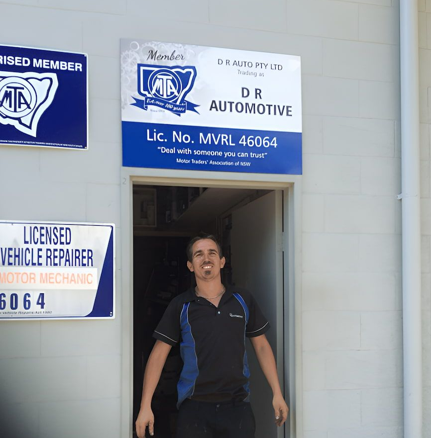 Man Standing in the Doorway of an Auto Repair Shop With Signs — D R Automotive in Russell Vale, NSW