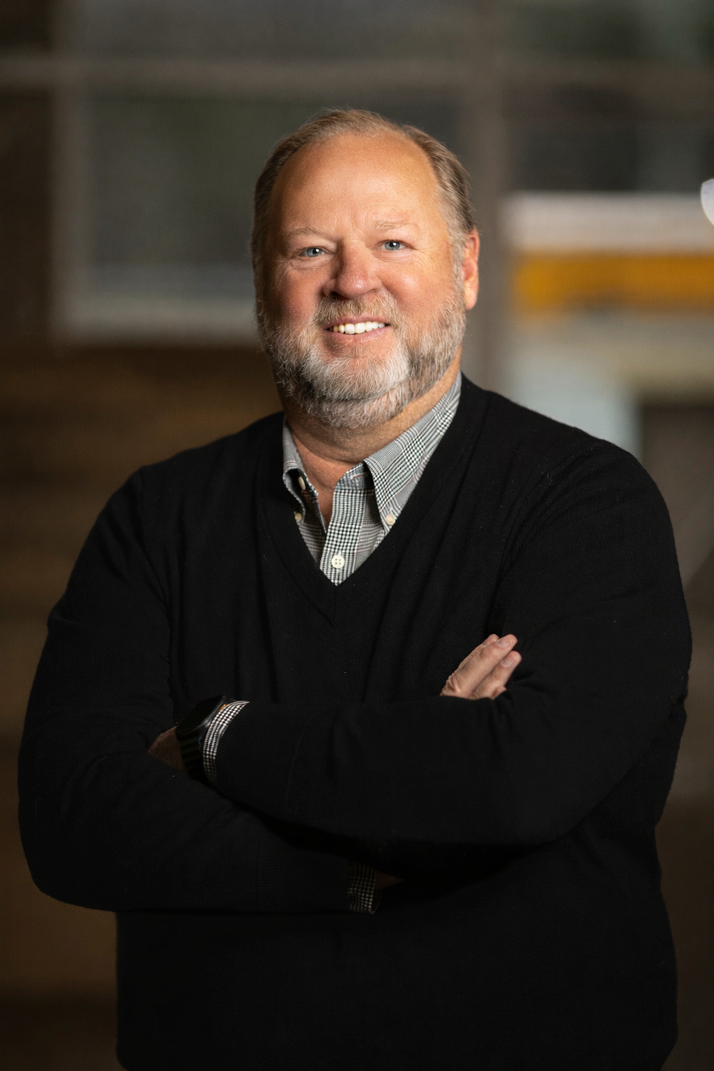 A man with a beard is wearing a black sweater and smiling.