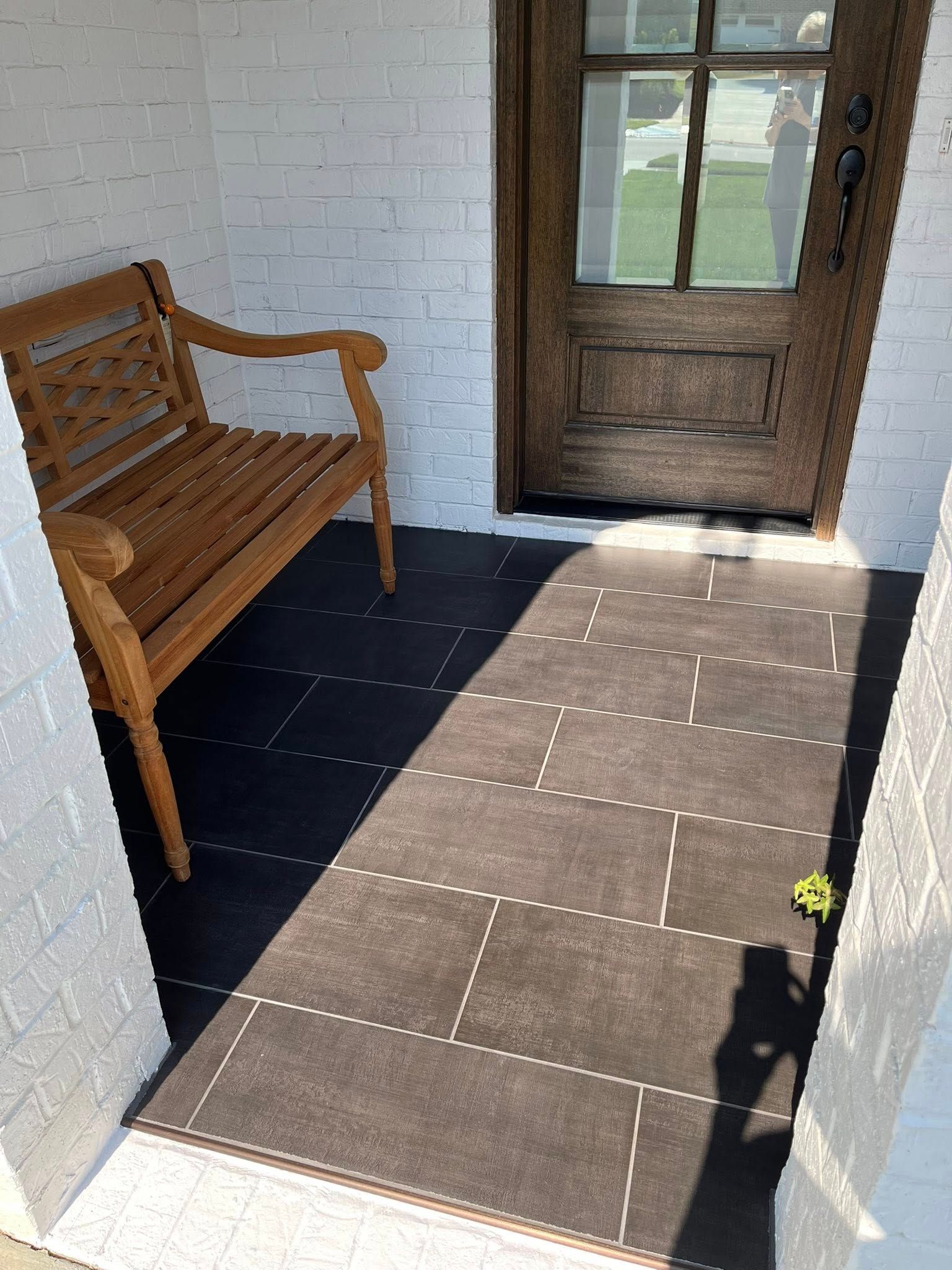 A wooden bench is sitting on a porch next to a door.