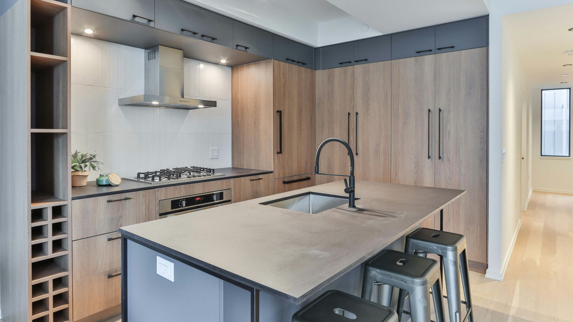 A kitchen with a large island , sink , stove and stools.