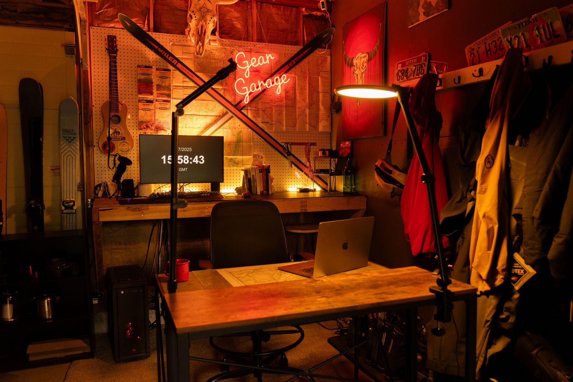 Cozy red-lit workshop with a wooden table, hanging coats, and a monitor on a cluttered desk