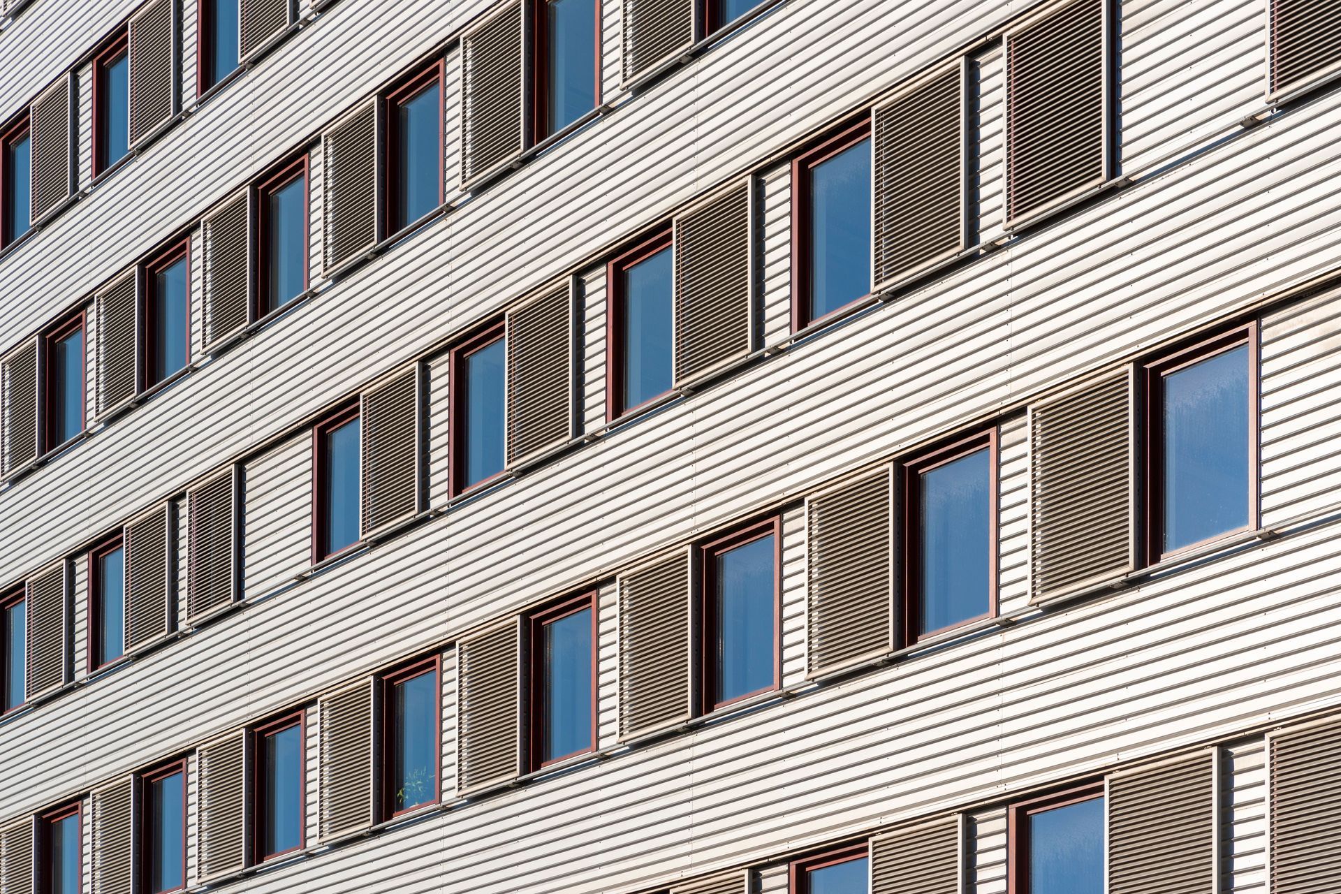 Diagonal view of a modern building facade with rows of windows and beige panels