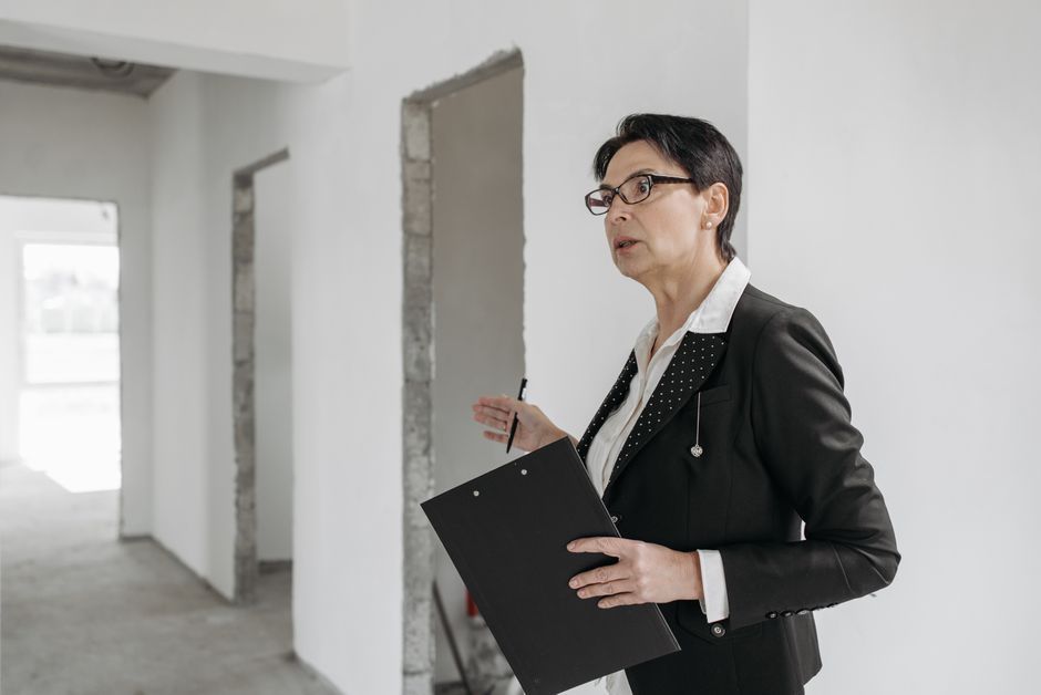Person holding a clipboard in a bright, unfinished room with white walls and open doorways